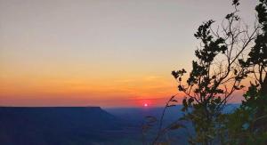 a sunset on the side of a mountain with a tree at Hostel Itapiru in Mateiros