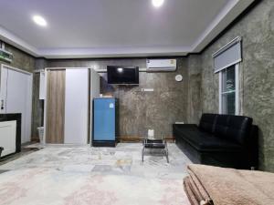 a living room with a black couch and a tv at The loft 2 in Ban Khlong Khwang Klang