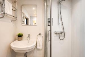 a white bathroom with a sink and a shower at Historic Dutch Barge, Idyllic location in London +17 photos