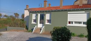 a green house with a white door and stairs at Entre vigne et Loire in La Coindassière
