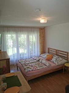 a bedroom with a bed and a table at Kaméleon Apartmanház EV töltéssel in Balatonszemes