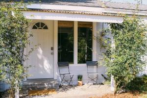 a white house with two chairs on the porch at Rock Rose Cottage in Trinidad