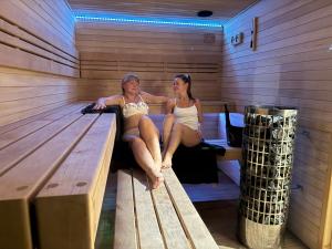 two women are sitting in a sauna at Leśna Polana Domki in Okuninka