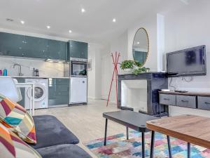 a living room with a couch and a tv and a kitchen at Le Grand Sault - Hyper-Centre in Grenoble