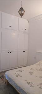 a white bedroom with white cabinets and a bed at Maison Souad Guest House in Chott Meriem