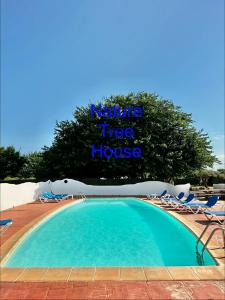 a swimming pool with chairs and a sign that reads nature tree house at Nature Tree House Casa sobre los árboles in Tordera