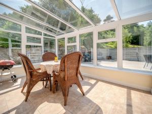 a conservatory with a table and chairs and windows at 3 Bed in Glengarrff oc-i089 in Glengarriff