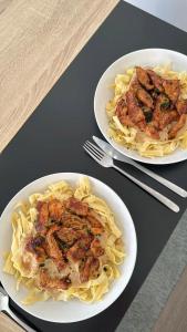 two plates of food with meat and pasta on a table at ERLAN Guest House in Jangy-Talap +2 photos