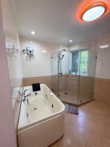 a large bathroom with a tub and a shower at Dolores Cabin & Breakfast in Mactan