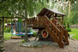a wooden playground with a slide and a tree at Domki Pod Lasem Lubkowo in Lubkowo