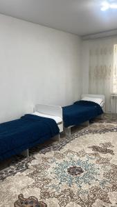 two beds in a room with a rug at ERLAN Guest House in Jangy-Talap