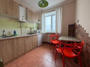 a kitchen with red chairs and a table and a sink at Соборная Апартаменты in Kamianets-Podilskyi
