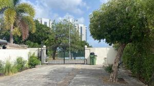 a gate in a driveway with a tree and a building at Appartement une chambre cupecoy in Cupecoy