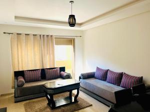 ein Wohnzimmer mit Sofa und Tisch in der Unterkunft Taj 3 in Nouaceur + 1 Foto