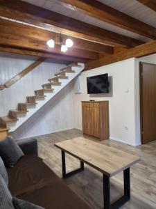 a living room with a table and a tv and stairs at Domek całoroczny Nad Stawem in Powidz