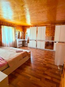 a bedroom with a bed and white cabinets and wooden floors at Guesthouse Tetnuldi in Kʼolashi