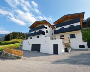 a white house with a wooden roof at Ferienwohnung Kogler Zillertal in Fügenberg