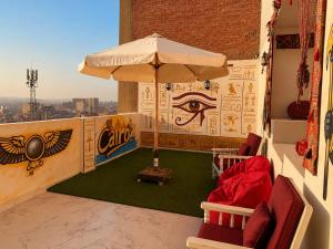 a balcony with an umbrella and chairs and an eye at Pyramids View Rooftop Apartment in Ghaţāţī