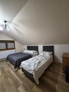 a bedroom with two beds and a wooden floor at Domek całoroczny Nad Stawem in Powidz
