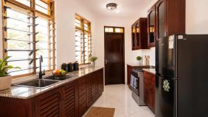 a kitchen with a black refrigerator and a sink at Greenfield Villa D- Diani in Diani Beach