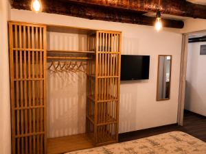 a room with a tv and a closet with wooden shelves at La Baita Delle Due Valli in Maccagno Superiore