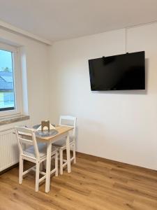 a dining room with a table and chairs and a flat screen tv at Sleep & Go Höchst in Höchst