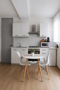 a white kitchen with a table and chairs in it at Lætitia Cottage Apartment in Aversa