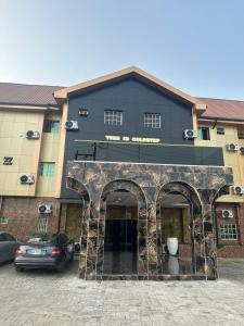 a black building with an archway in a parking lot at Goldstep Hotel Effurun in Warri