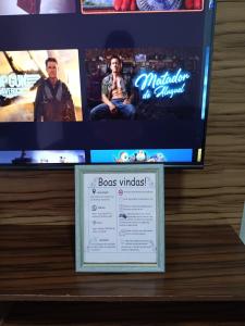 a tv and a sign on a shelf with a picture at Casa com churrasqueira – Próx. Shopping Comércios in Várzea Paulista