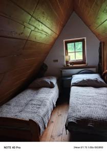 two beds in a attic room with a window at Kamienna Polana in Wapienne