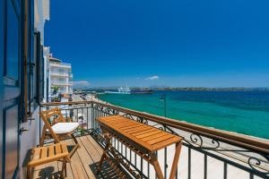 balkon z dwoma drewnianymi krzesłami i widokiem na ocean w obiekcie Aisthesis w mieście Spetses