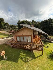 a house with a large deck in the grass at POUSADA QUINTAL DAS OLIVEIRAS in Monte Verde