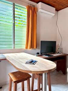 a kitchen with a table and a desk with a computer at Le paradis créole in Sainte-Luce