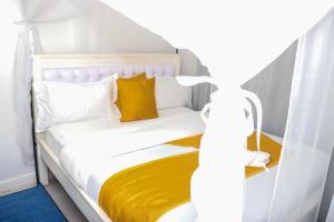 a white bed with yellow sheets and pillows at HOBRA HOMEs -Naivasha B in Naivasha