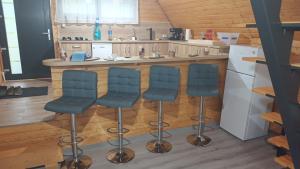 a kitchen with three bar stools and a refrigerator at Cabana A frame Nămăiești in Nămăeşti