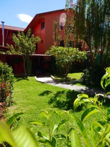 a green yard with a red building and a driveway at Hotel Tambo del Valle in Urubamba