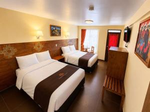 a hotel room with two beds and a chair at Hotel Tambo del Valle in Urubamba
