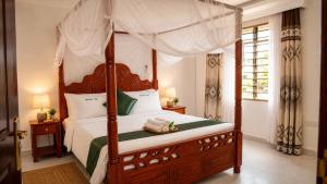 a bedroom with a four poster bed with a canopy at Greenfield Villa D- Diani in Diani Beach +21 photos
