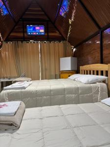 two white beds in a room with a tv at RECANTO CANTAGALO Hotel in Cantagalo