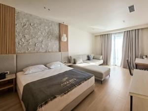 ein Hotelzimmer mit zwei Betten und einer Couch in der Unterkunft Avaris Hotel in Dhërmi