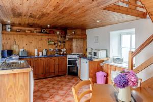 a kitchen with wooden cabinets and a table with a vase of flowers at 2 Bed in Cashel oc-i223 in Moyrus