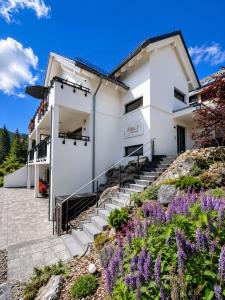 a white building with stairs and purple flowers at Villa Number 8 in Feldberg