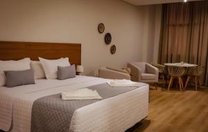 a bedroom with a large bed and a table and chairs at Amazon Seasons Suíte Premium em Belém in Belém