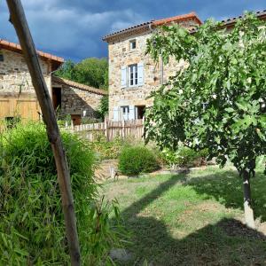 a stone house with a tree in a yard at La Pierre du Grain in Ravel
