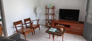 a living room with a tv and two chairs and a table at 36 Baltazia, 2 Ch 2 Pers-Clim jardin terrasse à Sainte-Anne in Sainte-Anne