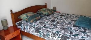 a bed with a black and white comforter and pillows at 36 Baltazia, 2 Ch 2 Pers-Clim jardin terrasse à Sainte-Anne in Sainte-Anne