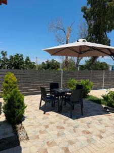 a table and chairs with an umbrella on a patio at Calliopi's studio in Plytra