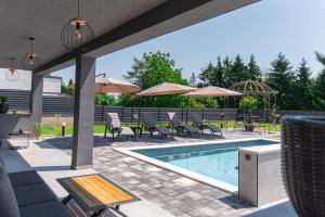 a swimming pool with chairs and tables and umbrellas at Villa Novara Holiday Home in Lužan Biškupečki