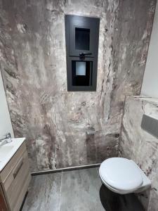 a bathroom with a toilet and a tv on the wall at Bed and breakfast ALDIANA in Cap Skirring +2 photos