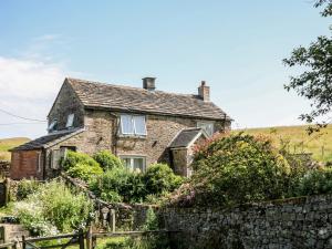 an old stone house with a stone fence at Overlea Cottage in Birch Vale